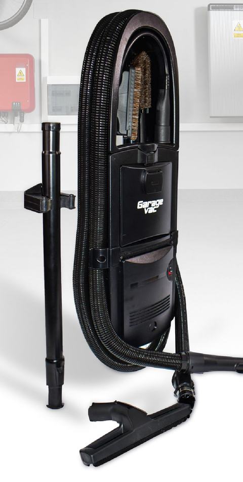 The GarageVac GH120 in ebony: the wall-mounted unit with its 35-foot hose coiled around it, cleaning tools stored in the top caddy, telescoping wand and bare-floor tool alongside.
